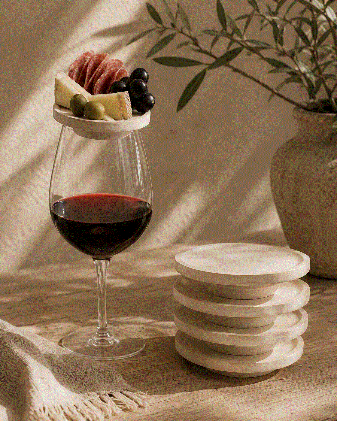 Charcuterie Wine Plates are round whitewashed wooden wine glass toppers, with one holding cheese, salami and olives