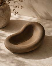 Decorative Concrete Tray in warm brown textured concrete, with an organic sculptural shape and deep curved basin