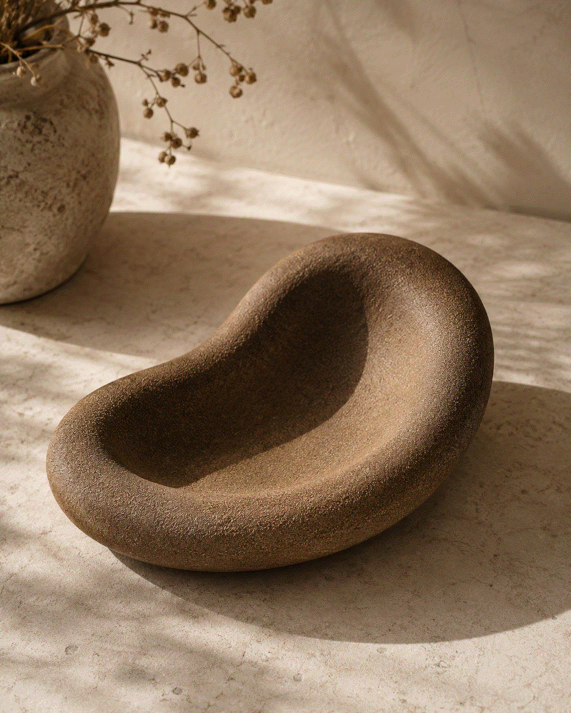 Decorative Concrete Tray in warm brown textured concrete, with an organic sculptural shape and deep curved basin