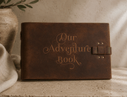 Story Keeper Leather Journal in distressed dark brown leather, embossed with “Our Adventure Book” and a buckle strap
