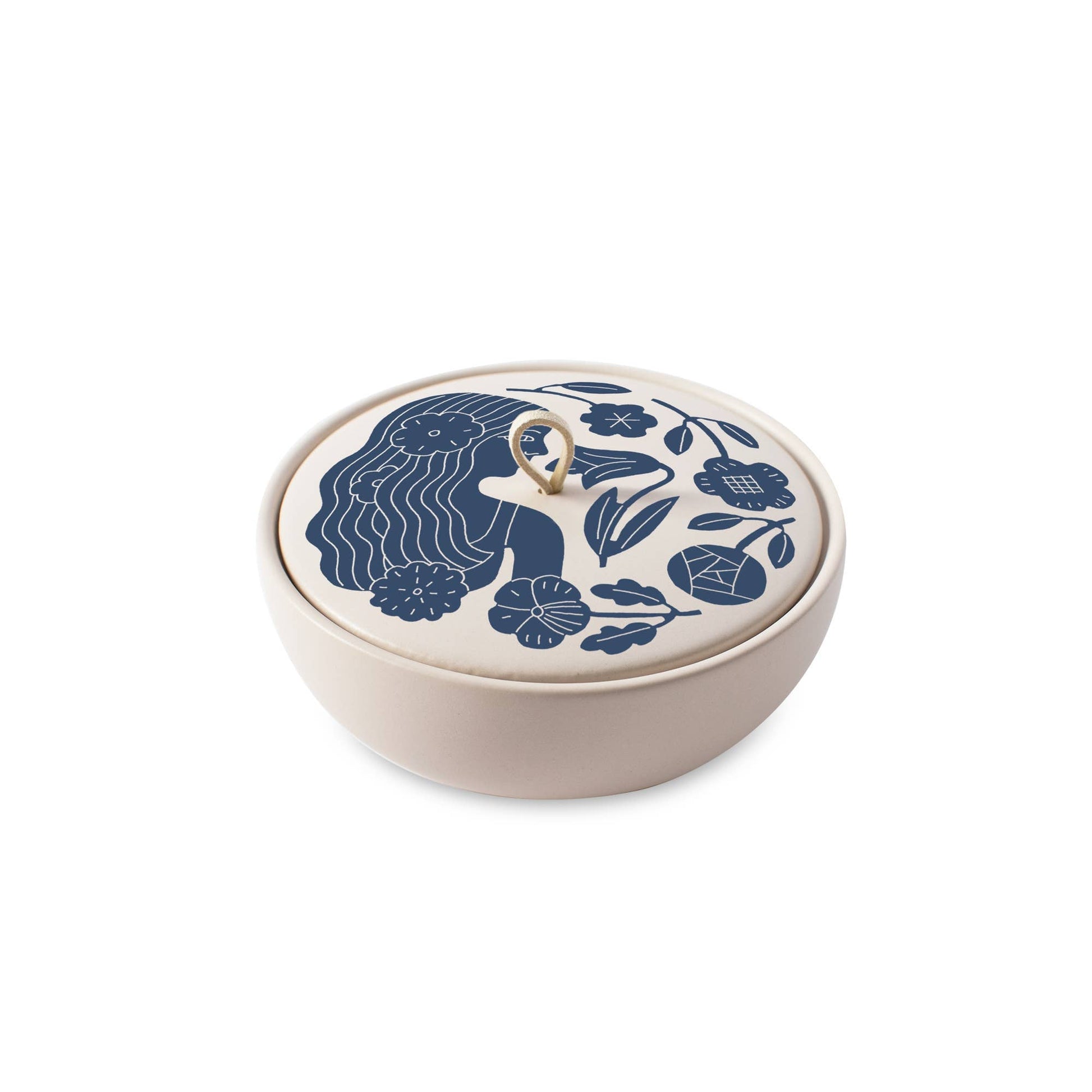 The Rooted Home ceramic trinket box with a matte cream finish, blue floral zodiac lid, and faux suede loop handle.
