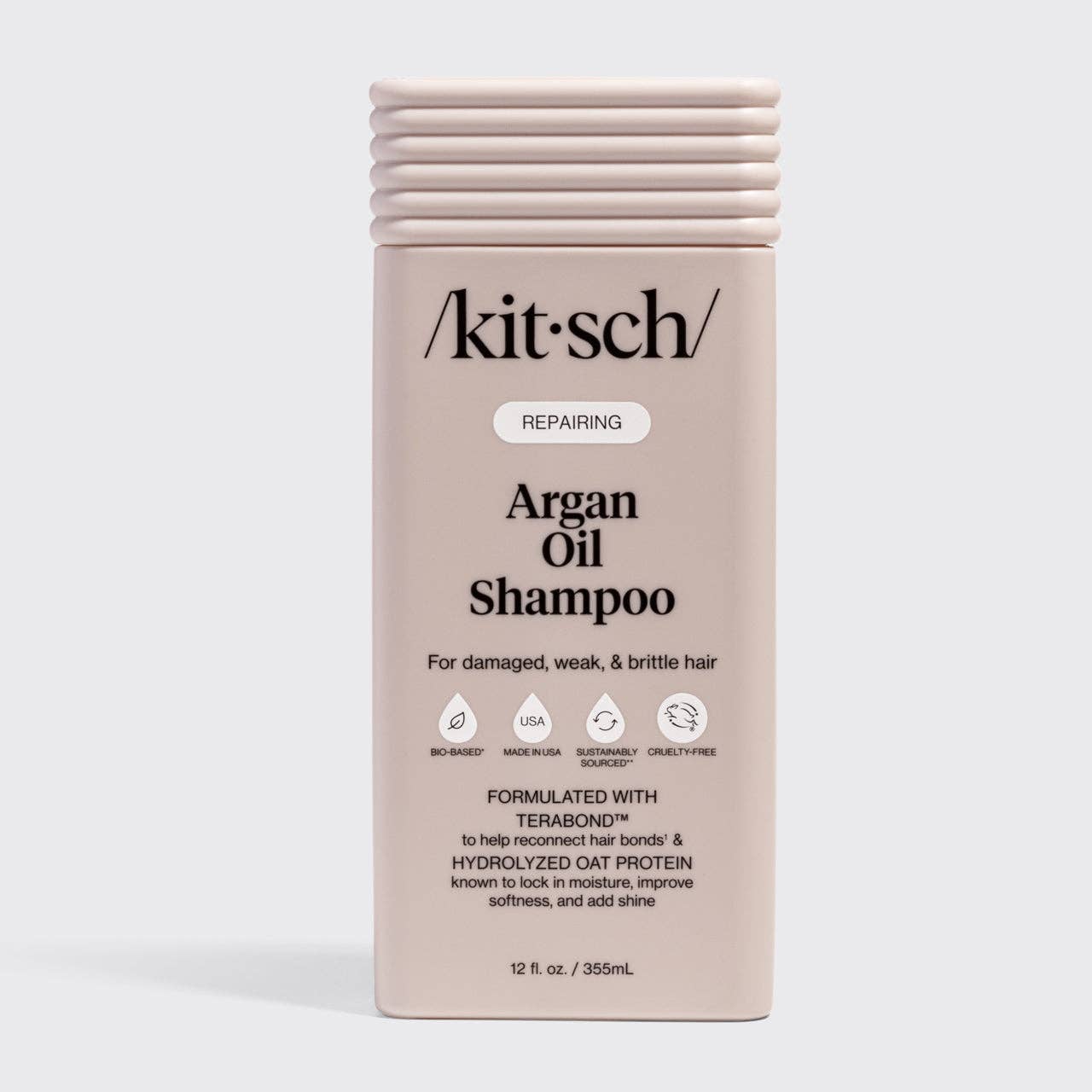 The Rooted Home Kitsch Repairing Argan Oil Shampoo in a light pink bottle for damaged, weak, and brittle hair.