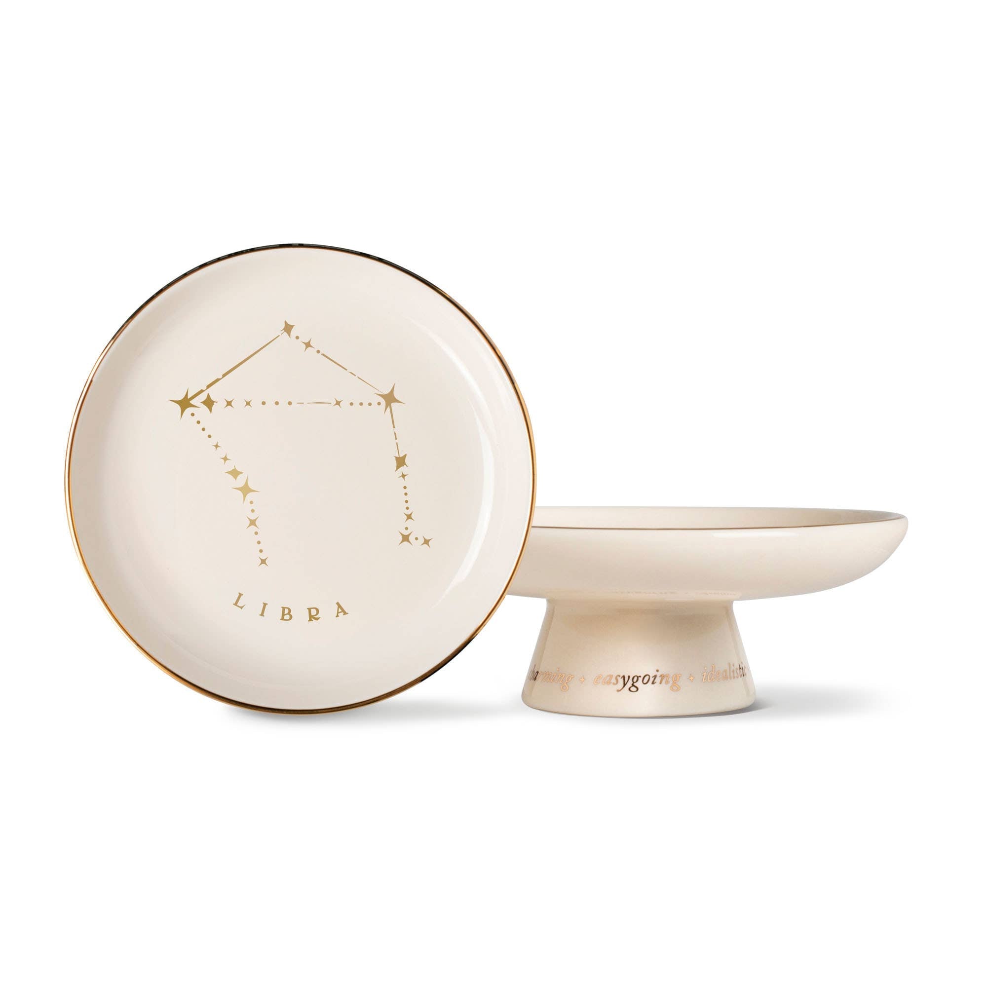 The Rooted Home Libra zodiac pedestal tray in cream stoneware with metallic gold foil constellation and text details.
